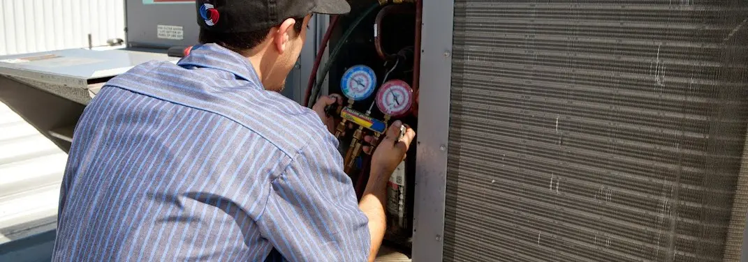 HVAC technician servicing a condenser unit in Maryville